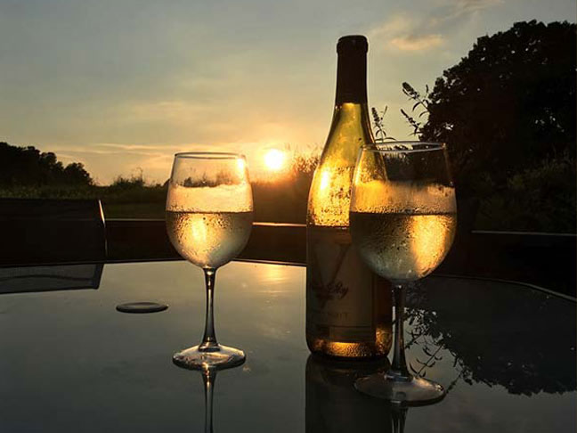 Bottle of white wine with two full glasses at sunset